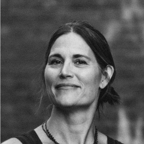 Rani Arbo ©Joanne Chattman composer Rani Arbo, a tall American woman with her hair in a ponytail, wearing a summer top and a wooden bead necklace