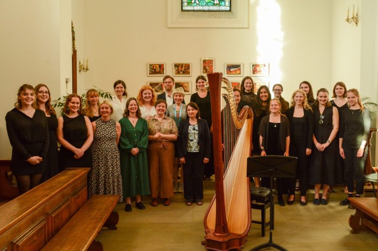 Young women of Somerville College Choir, Oxford, with their conductor Will Dawes, harpist Aoife Miralles and conference speakers from MoV.