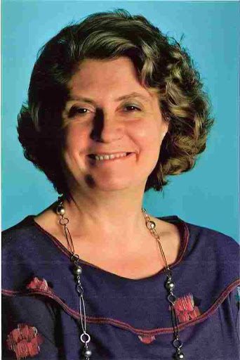 Bianca Maria Furgeri - photographer unknown composer Biana Maria Furgeri circa 1985, with thick wavy brown hair, a blue top decorated with red flowers and a long silver necklace