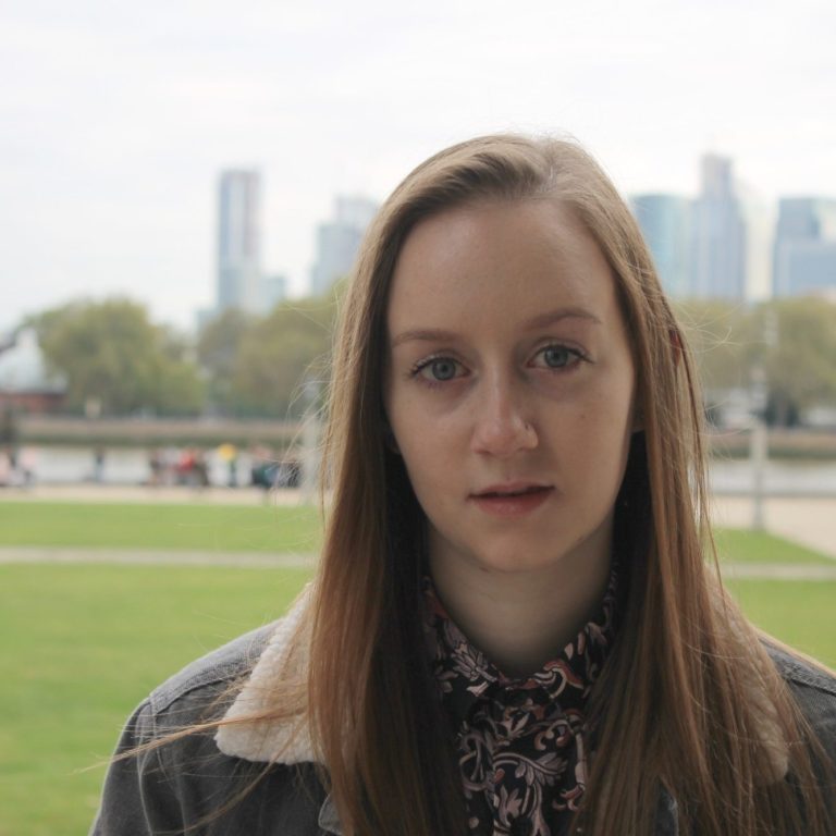 Amy Summers ©Amy Howe young composer Amy Summers stands outside in a public park. In the background are high-rise buildings