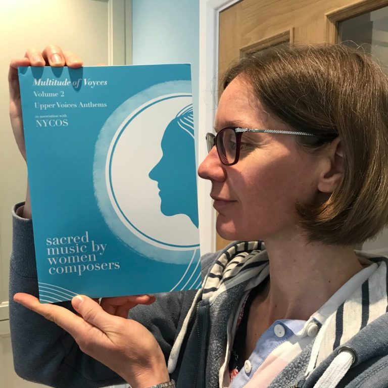 Amy Bebbington composer Amy Bebbington standing sideways to the camera holding a copy of MoV Volume 2 parallel to her face showing a similar profile