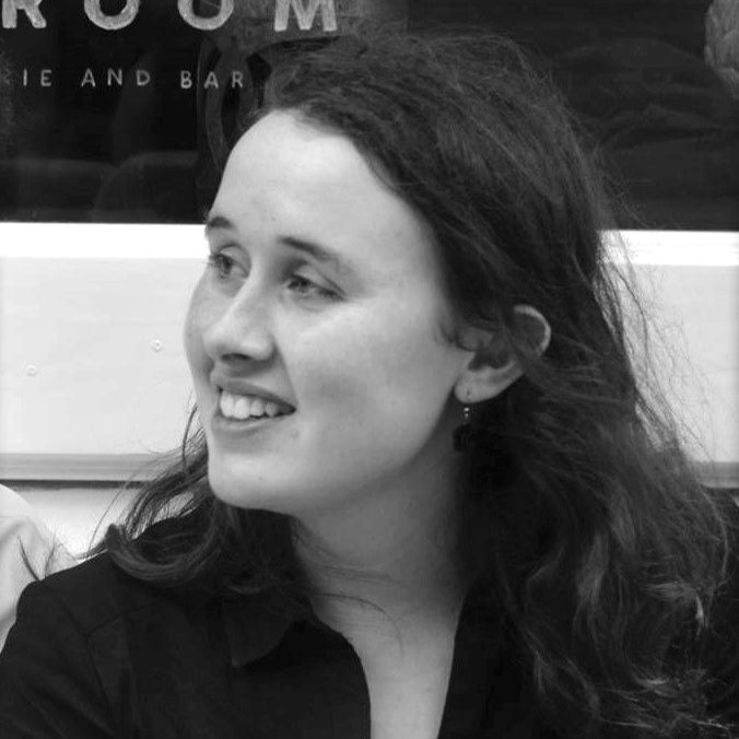 Emily Hazrati - photographer unknown black and white photo of young composer Emily Hazrati with long wavy brown hair and a black top smiling away from the camera