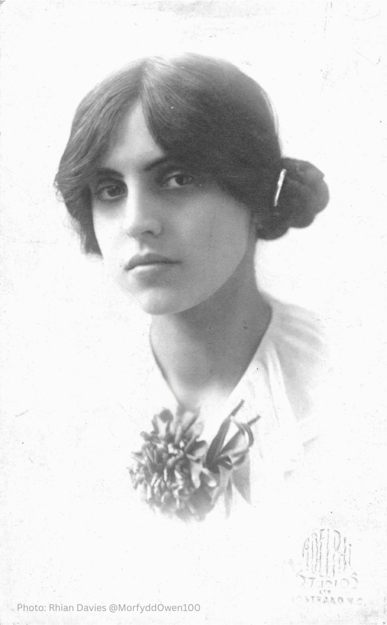 composer Morfydd Owen circa 1920 with thick dark hair loosely pulled into a bun, wearing a white lace blouse with decoration 