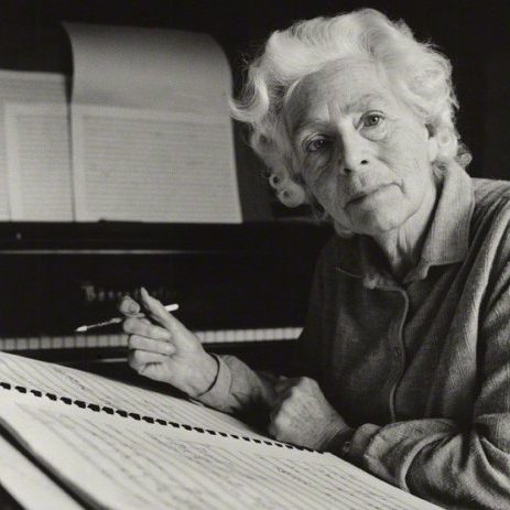 Dame Elizabeth Maconchy - ©British Music Collection Dame Elizabeth Maconchy circa 1977 with white wavy hair, sitting composing at a large manuscript book, behind is a grand piano with music